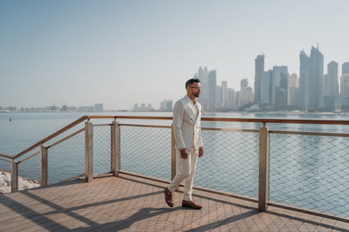 Walking Man Wearing White Suit Beside Fence