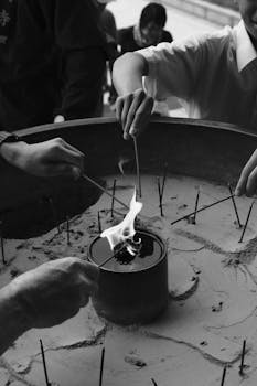 Group of people lighting incense sticks in a traditional ceremony.