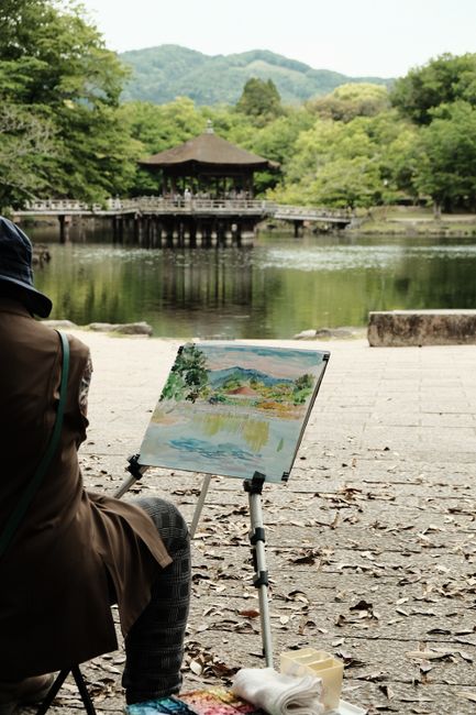 A serene scene of an artist painting by a tranquil lakeside with lush greenery.