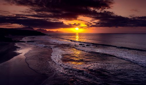 Free Serene sunset view with dramatic clouds over ocean waves. Stock Photo