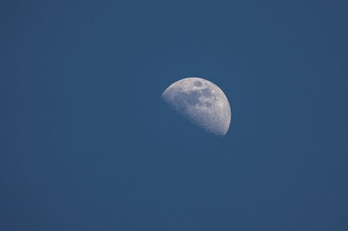 Free A detailed crescent moon set against a vibrant blue daytime sky. Stock Photo
