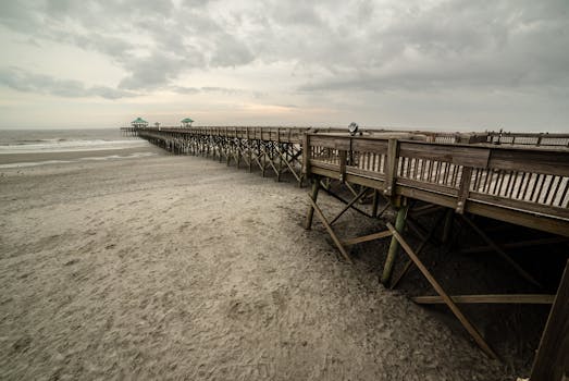 Scenic view of the wooden pier at Folly Beach, South Carolina, under a cloudy sky.