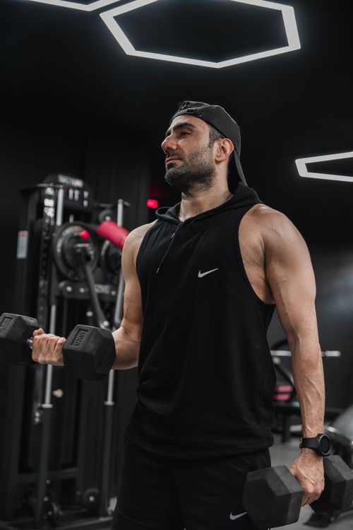 Free Fit man working out with dumbbells in a sleek, modern gym setting focused on strength. Stock Photo