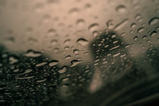 Macro view of raindrops on a window, creating a blurry cityscape background.