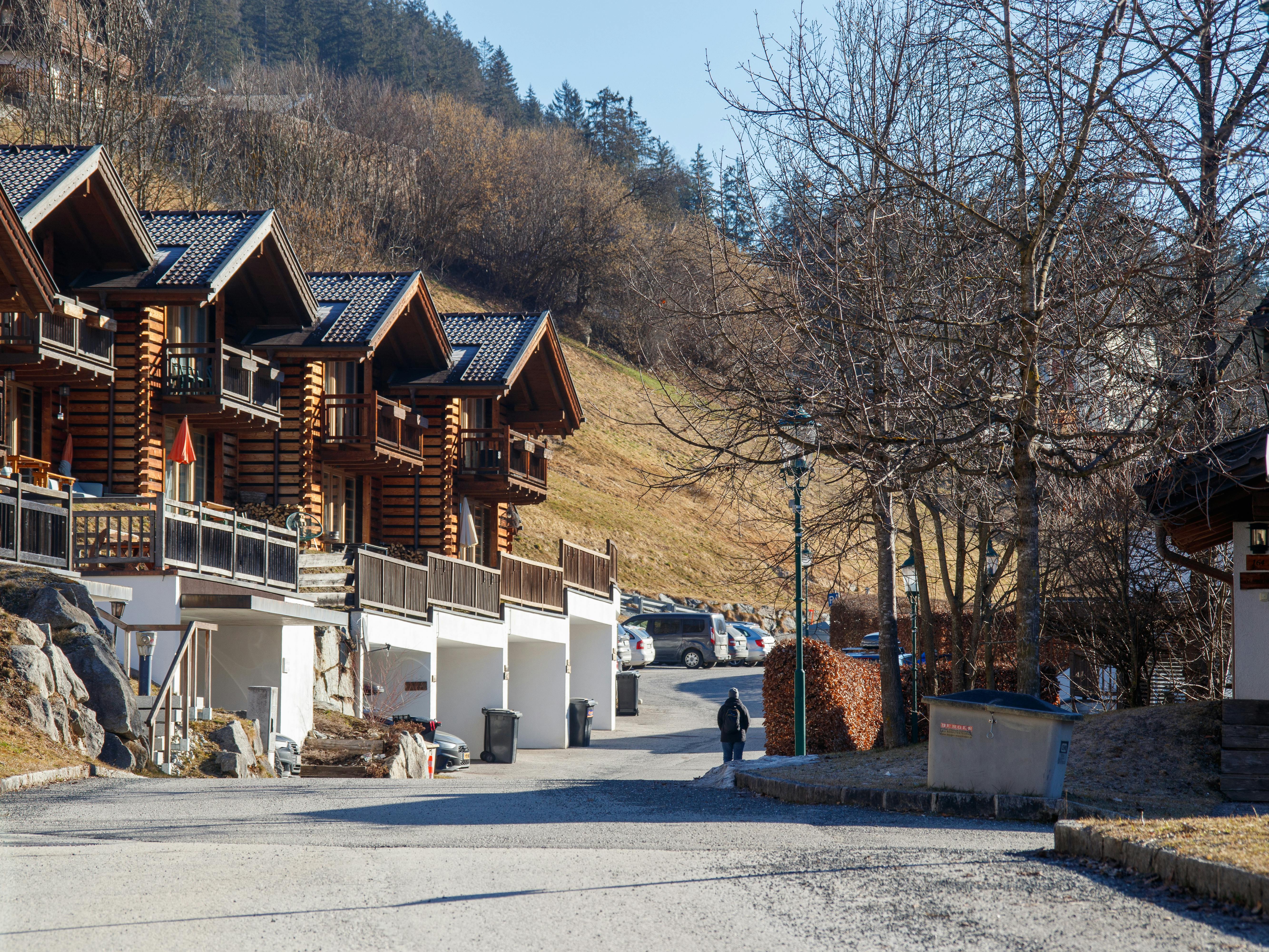 Rustic wooden cabins in a serene mountain village setting on a clear day.