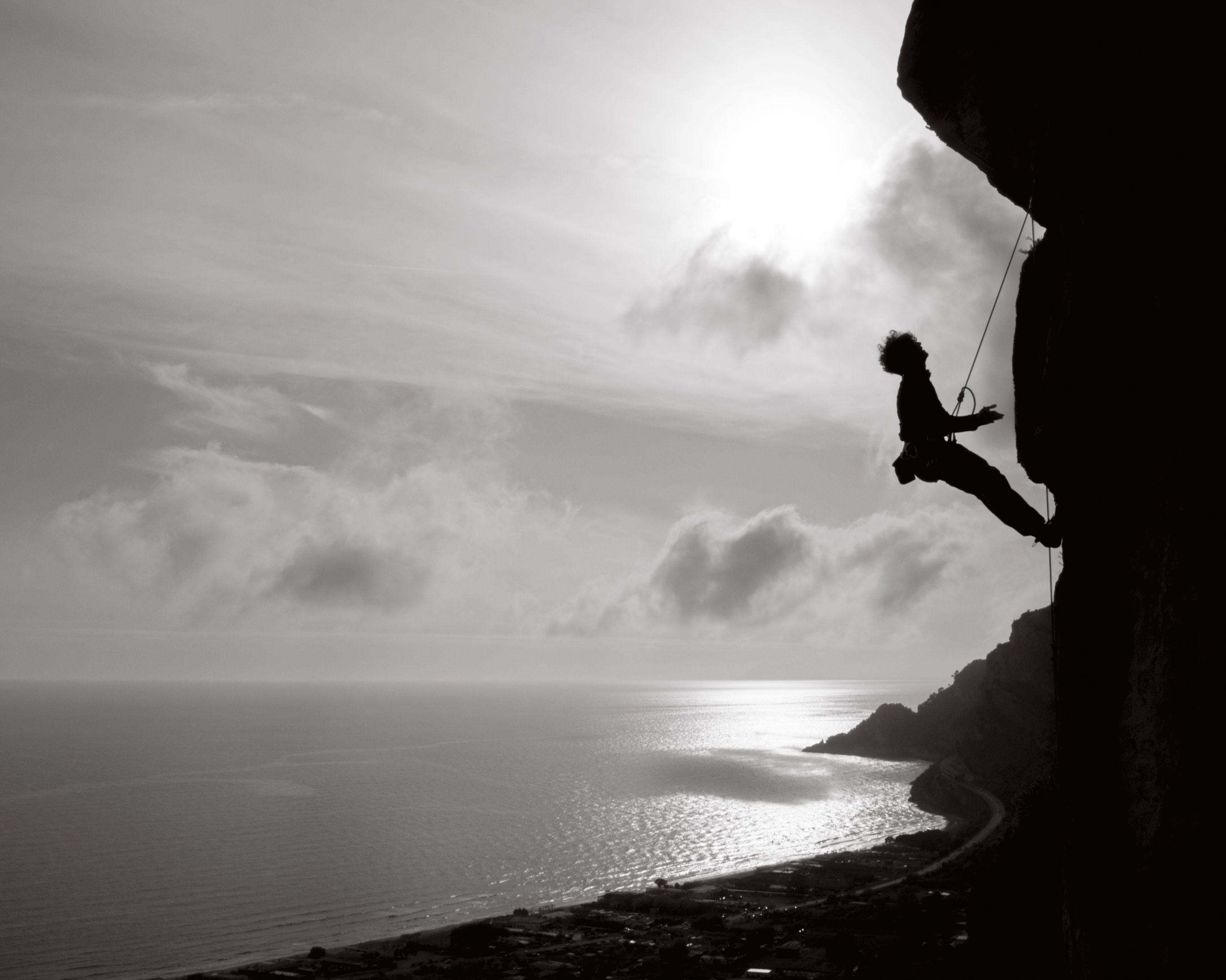 Silhouette of a climber on a cliff with scenic ocean view in Sperlonga, Italy.
