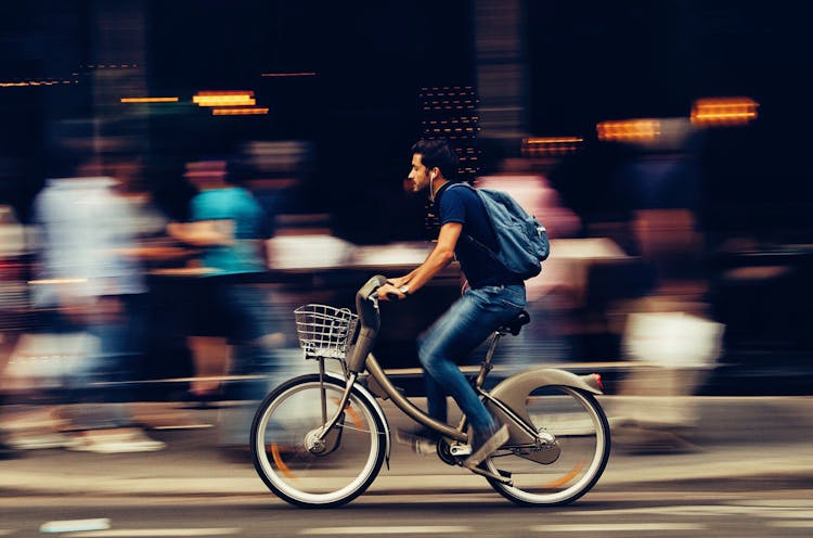 Man Riding Bicycle On City Street 