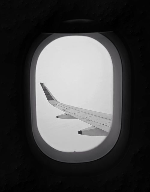 Free Black and white shot of airplane wing seen through window mid-flight, minimalist aesthetic. Stock Photo