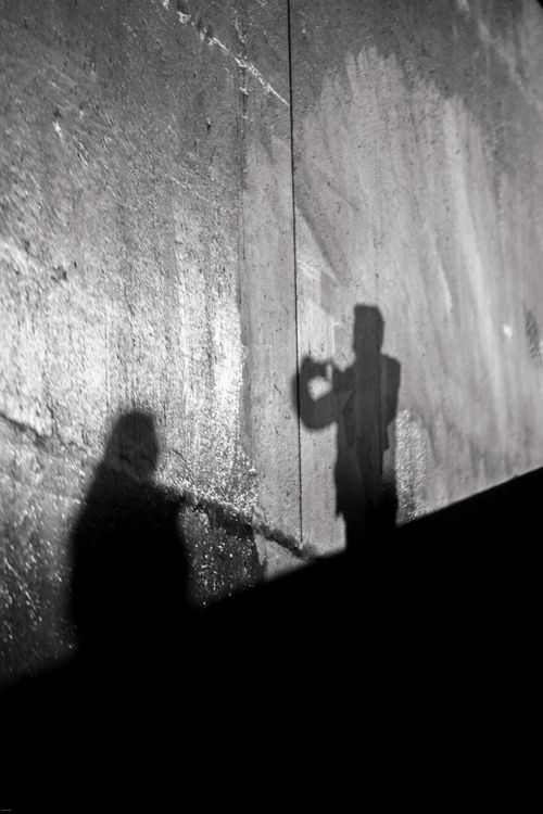 Free Abstract shadows of two people on a concrete wall, creating a mysterious urban scene. Stock Photo