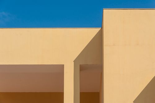 Free Minimalist architecture with geometric shadows and clear blue sky creates a striking abstract composition. Stock Photo