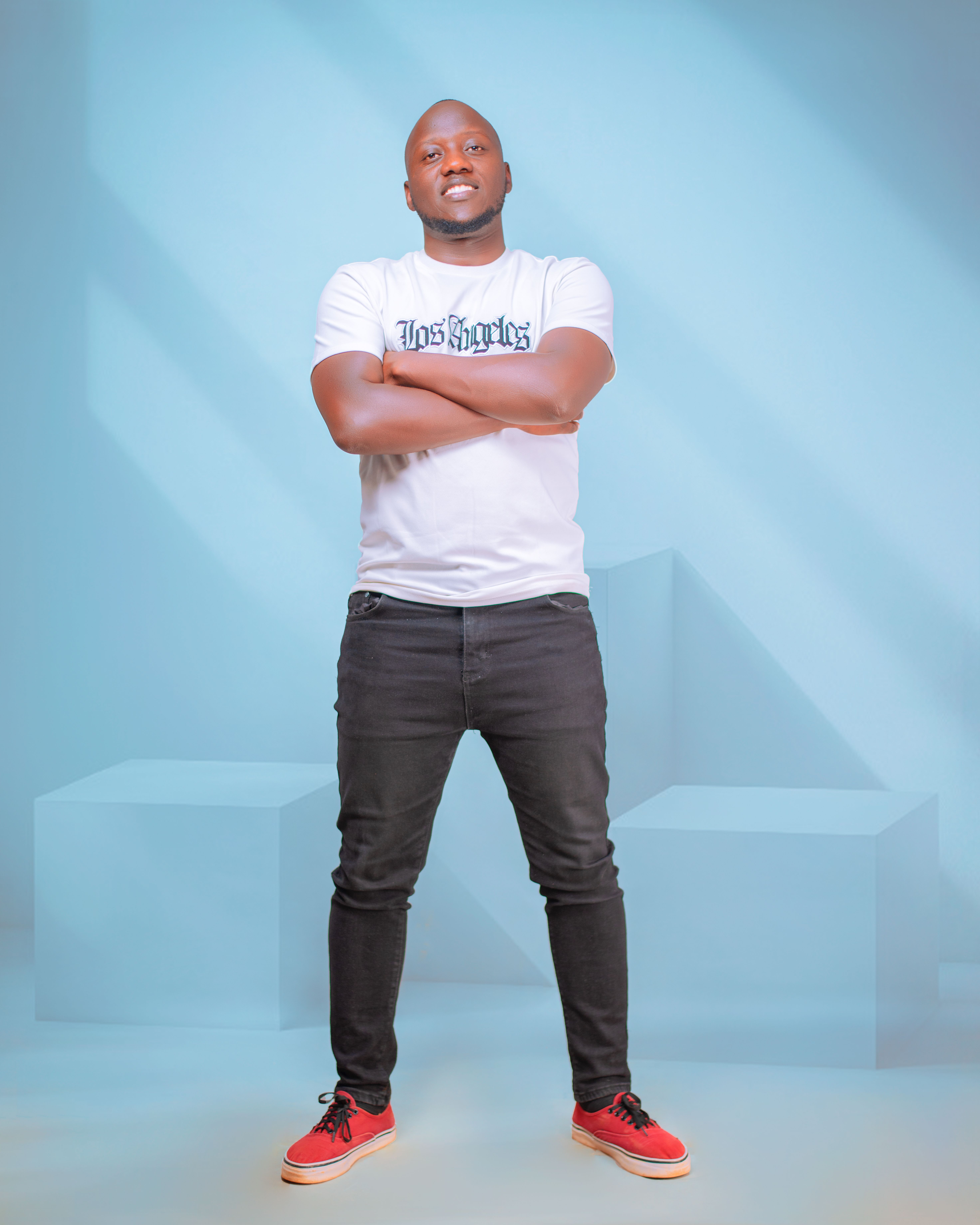 Young adult in casual wear posing confidently in studio setting.