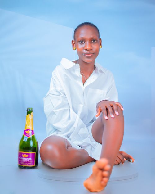 Free Woman in white shirt posing with a bottle on a minimal studio background. Stock Photo