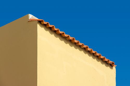 Free Simple, elegant structure featuring terracotta roof against a vivid blue sky, showcasing minimalist architecture. Stock Photo