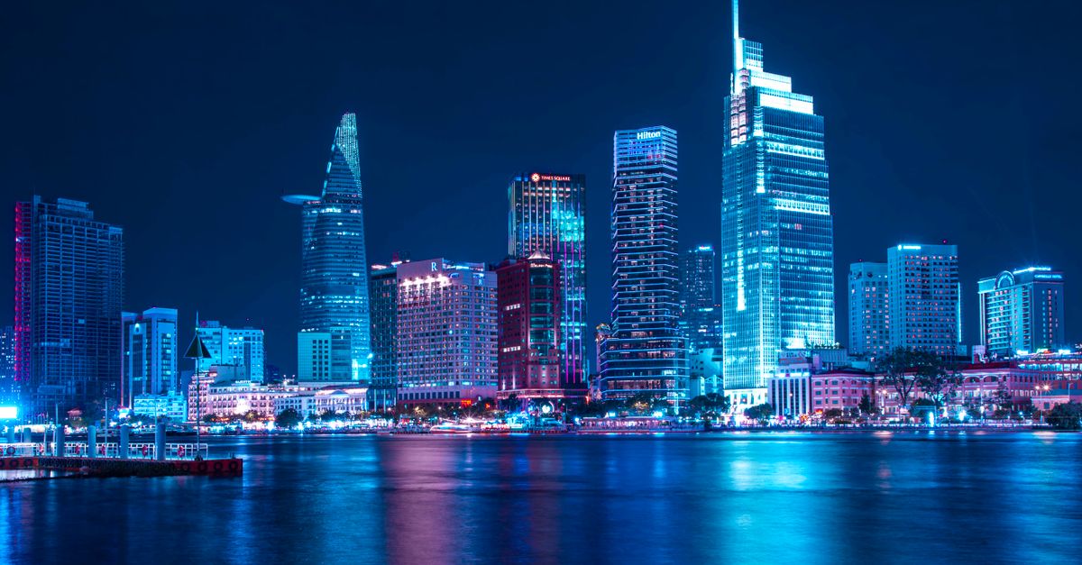 Aerial view of Ho Chi Minh City skyline at sunset with neon lights reflecting on the Saigon River