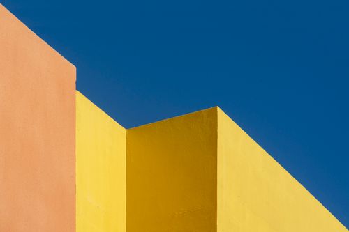 Free Colorful abstract architecture with geometric wall shapes against a vivid blue sky. Stock Photo