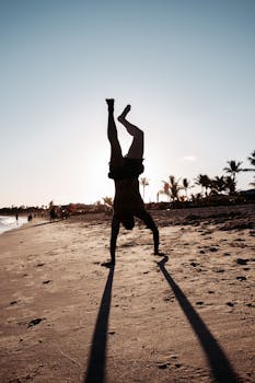 Silhouette of a man doing a handstand on a sunny beach in Porto Seguro, Brazil.