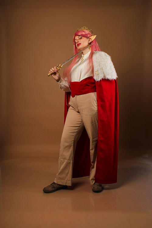 Free Colorful cosplay character with pink hair and red cape in a studio. Stock Photo