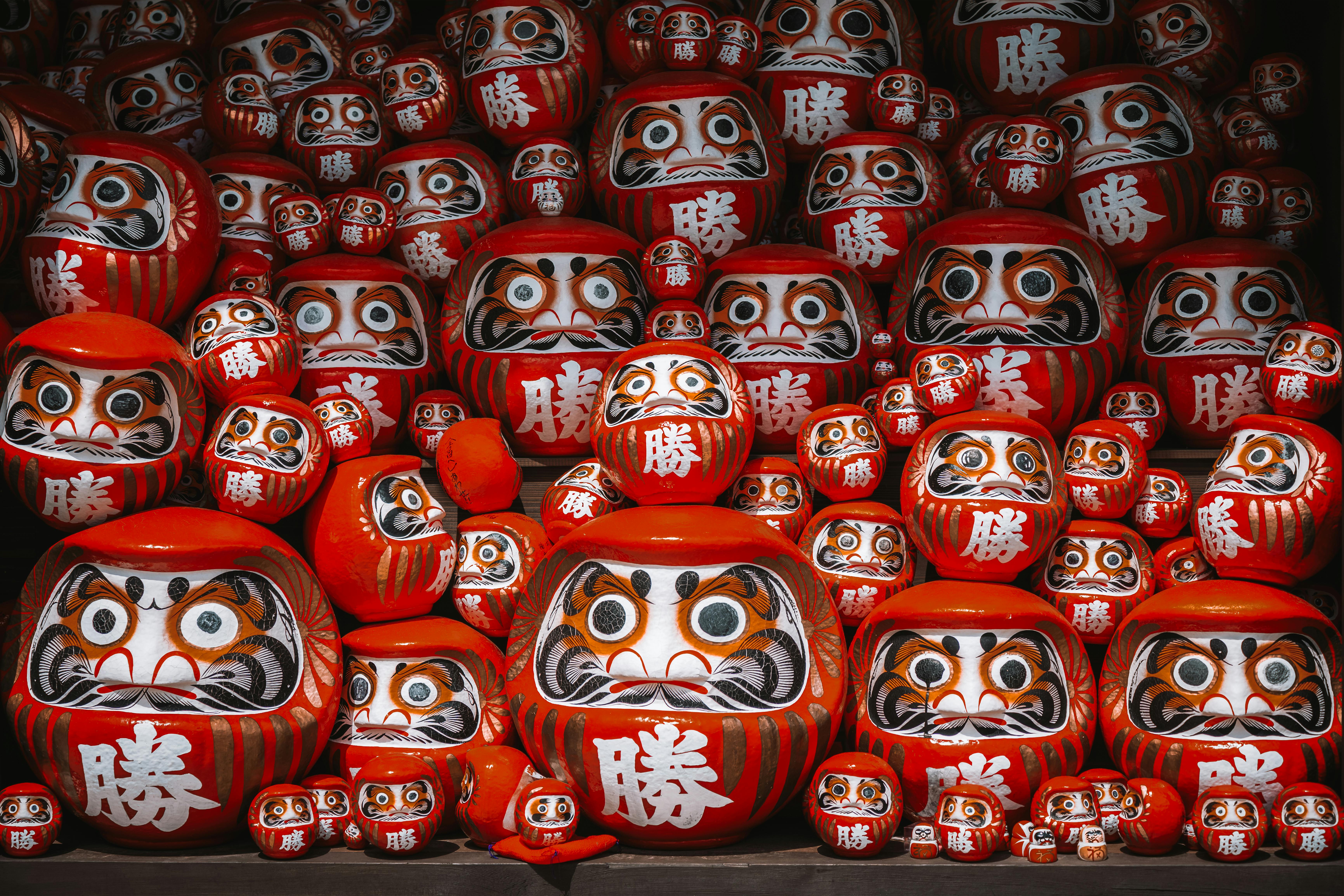 A collection of traditional red Daruma dolls at a Japanese temple, symbolizing perseverance and good luck.
