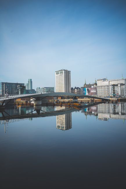 Stunning reflection of Copenhagen skyline and bridge on a calm day.