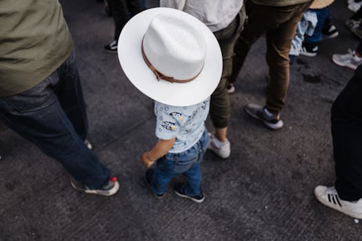 A child in a white hat standing among adults in a busy street in Tultepec, Mexico.