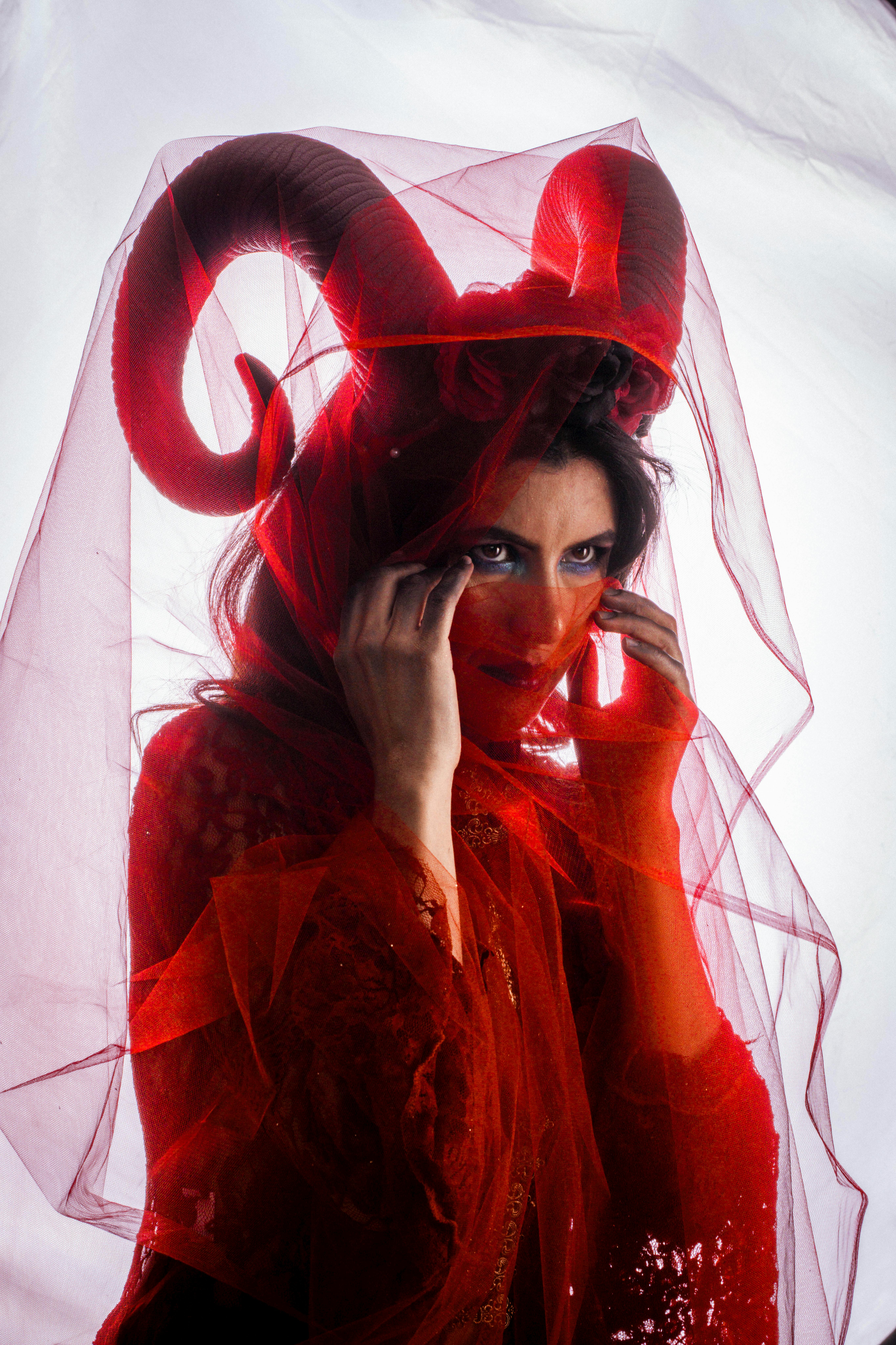 grátis Um retrato cativante de uma figura misteriosa em traje vermelho com chifres e véu. Foto profissional