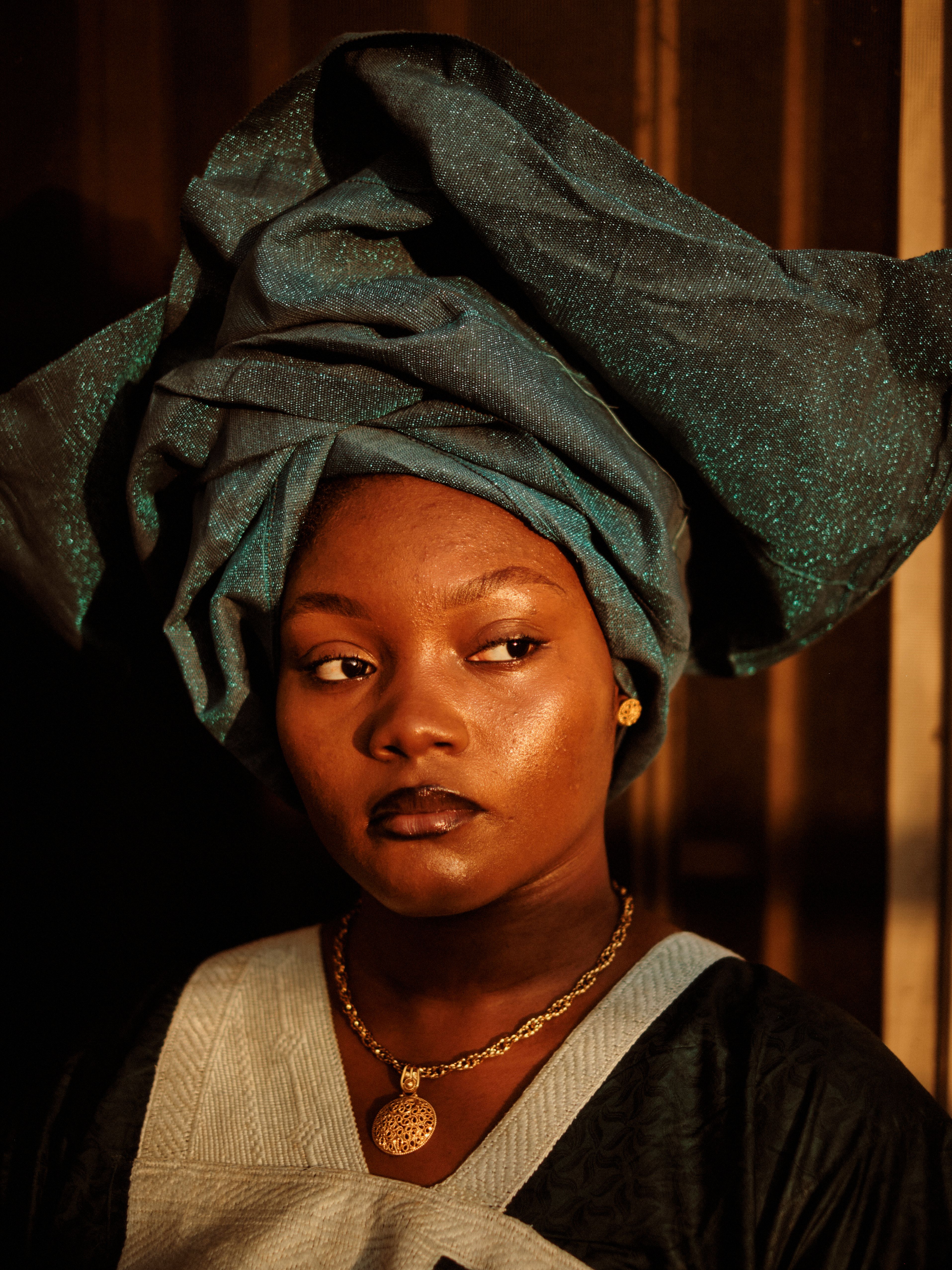 A striking portrait of a woman in traditional attire with a turquoise headwrap, exuding confidence.