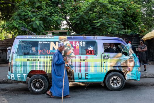 Vibrant graffiti-covered matatu in Mombasa, Kenya, with local pedestrians around.