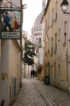 Explore a picturesque alleyway in Montmartre with Sacré-Cœur in the background, Paris, France.