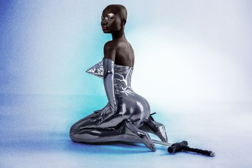 Free A striking portrait of a model in futuristic silver attire against a gradient blue background. Stock Photo