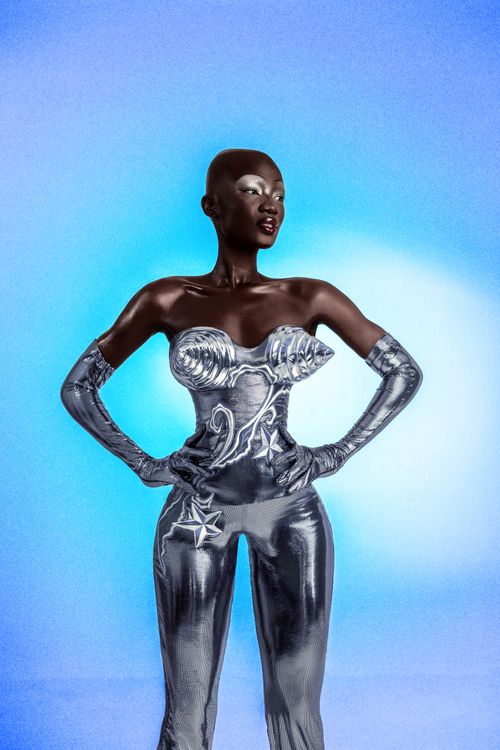 Free A striking portrait of a woman in silver futuristic attire with a blue gradient backdrop. Stock Photo
