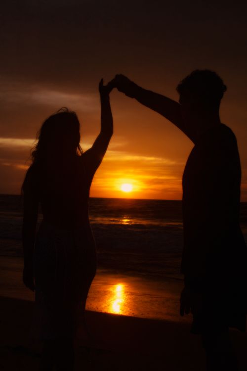 Free Silhouette of a couple dancing on a beach during sunset, evoking a sense of romance and tranquility. Stock Photo