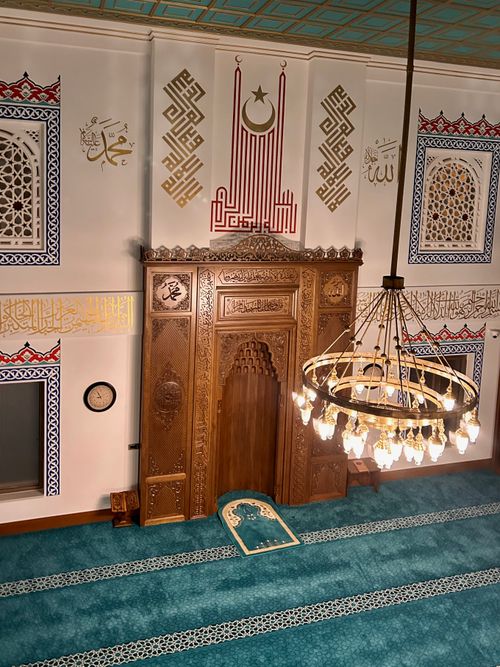 Free Stunning mosque interior featuring a wooden mihrab, intricate patterns, and a grand chandelier. Stock Photo