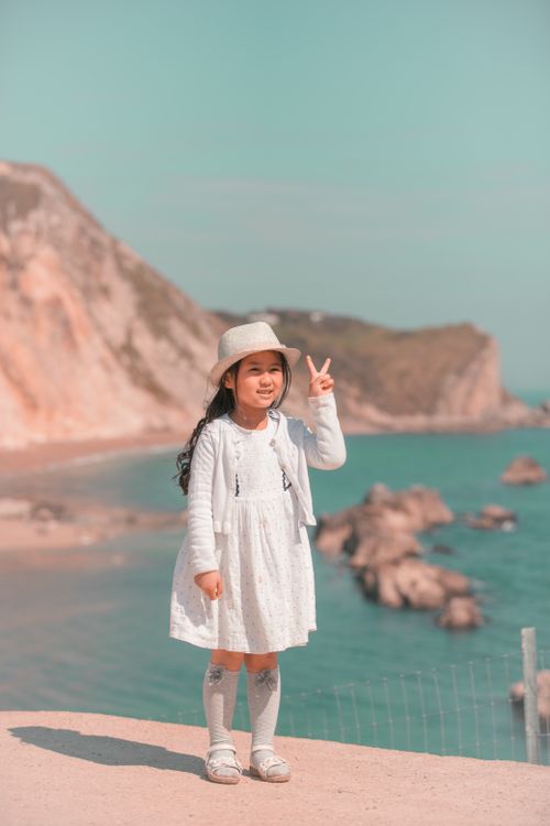 Free A young girl poses joyfully by the scenic Onna Beach in Okinawa on a sunny day. Stock Photo