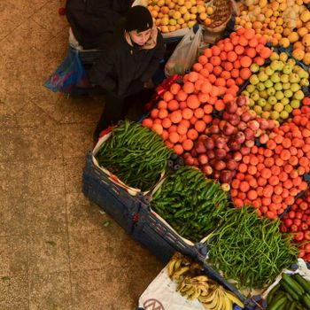 Aerial view of a market stall displaying colorful fresh produce with a vendor overseeing.