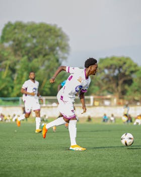 Soccer players in action during a daylight game outdoors on a green field.