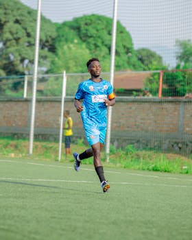 Soccer player running on field during a daytime match outdoors.