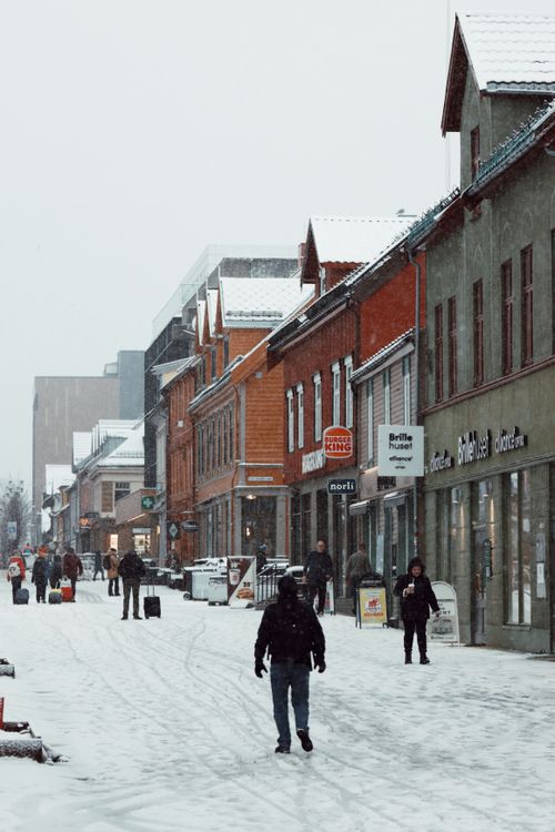Free Charming winter street in Tromsø, Norway, with people and snow-covered buildings. Stock Photo