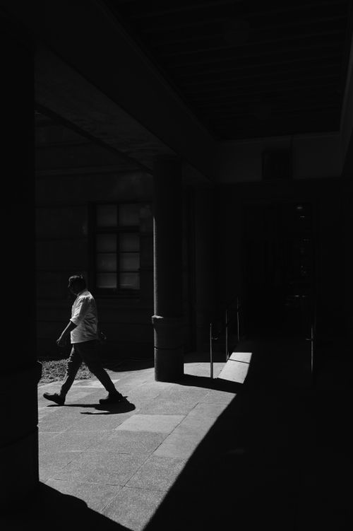 Free A person walking through a shadowed alleyway in Taiwan, creating a dramatic silhouette. Stock Photo
