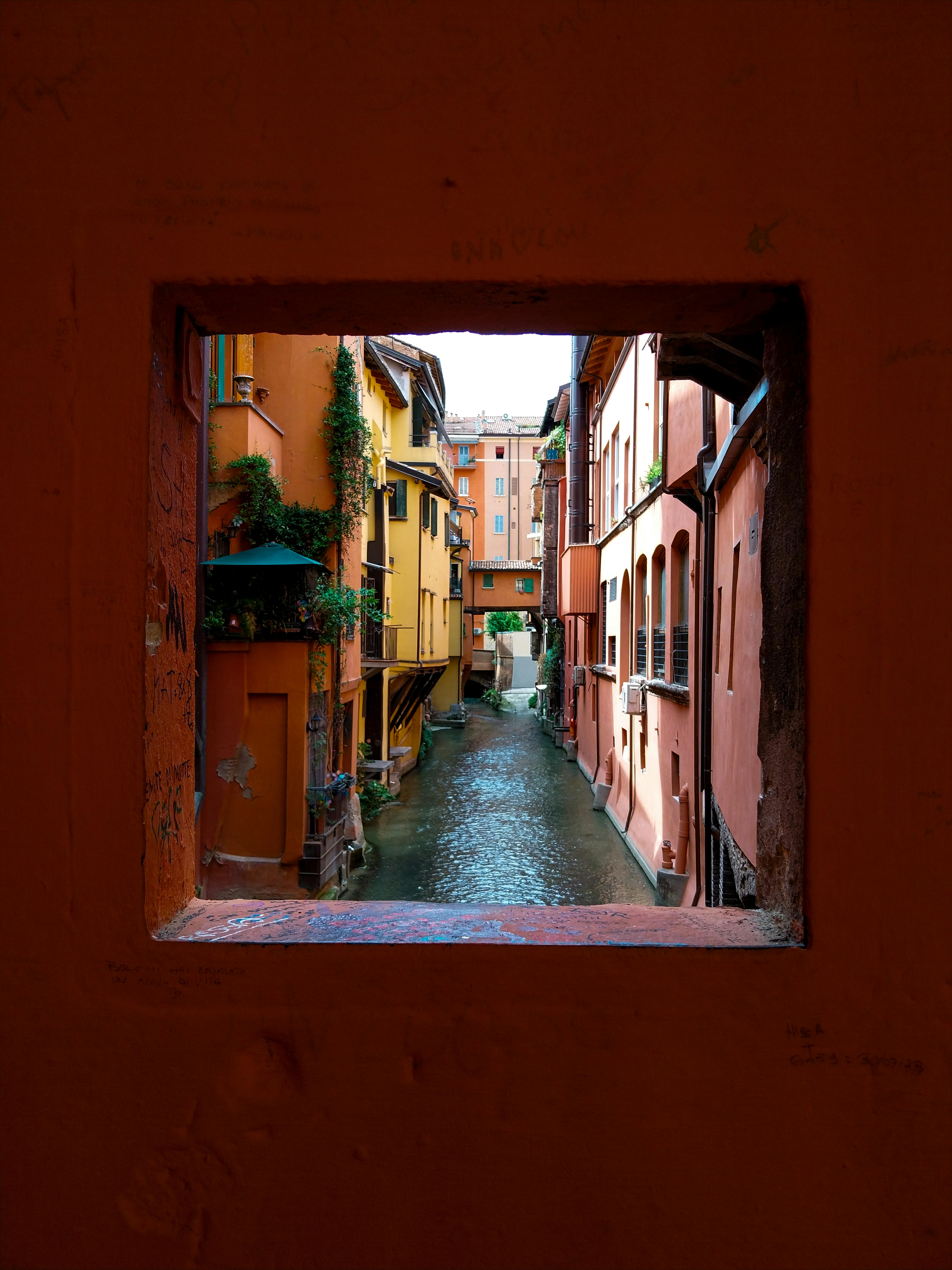 [ColoSach]-a-framed-view-through-a-window-of-bologna's-colorful-and-historic-canals.