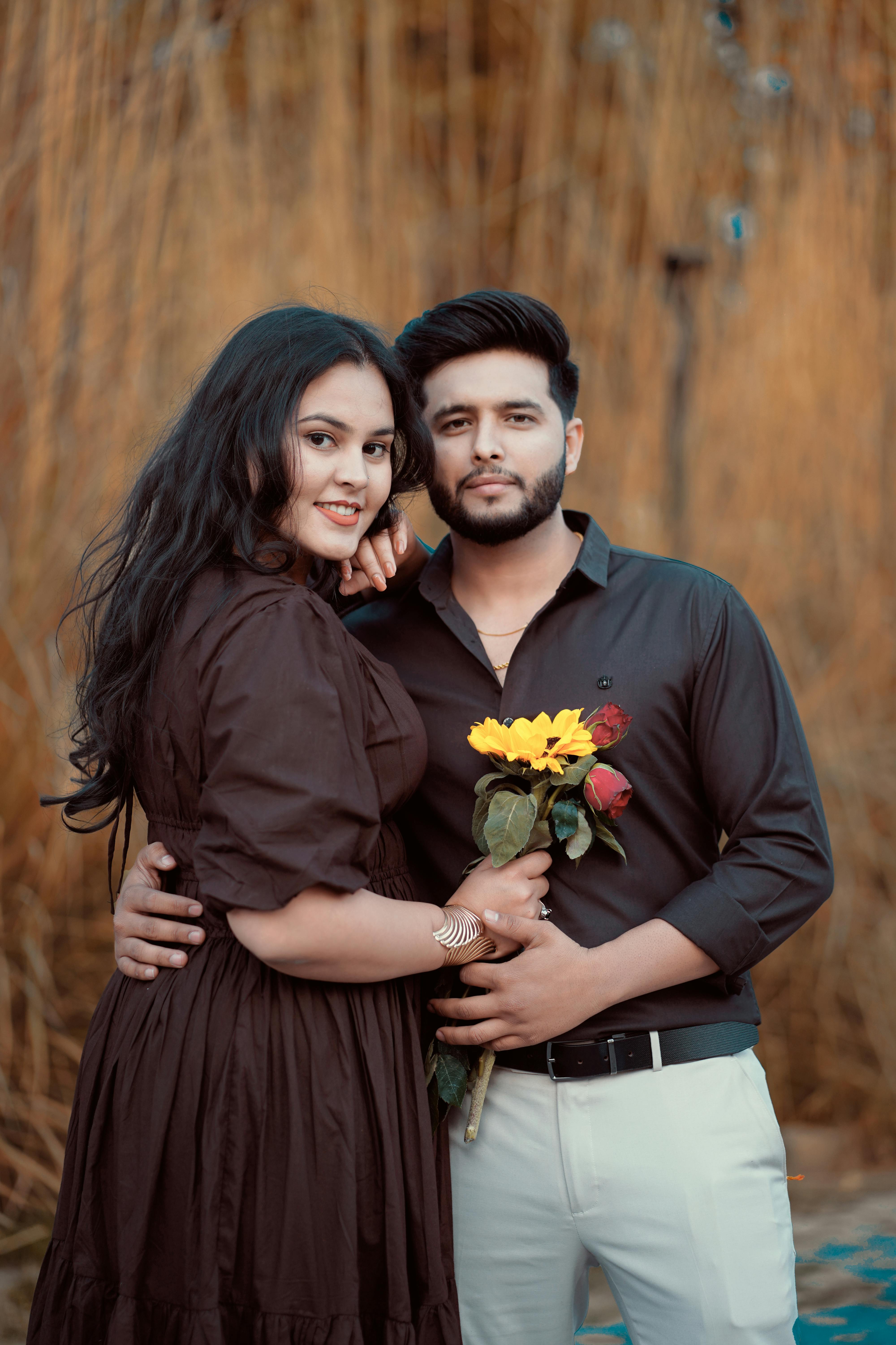 A couple embraces during a romantic outdoor photoshoot holding flowers.