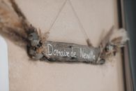 Close-up of a rustic wooden sign reading 'Domaine de Neuville' adorned with dried flowers.