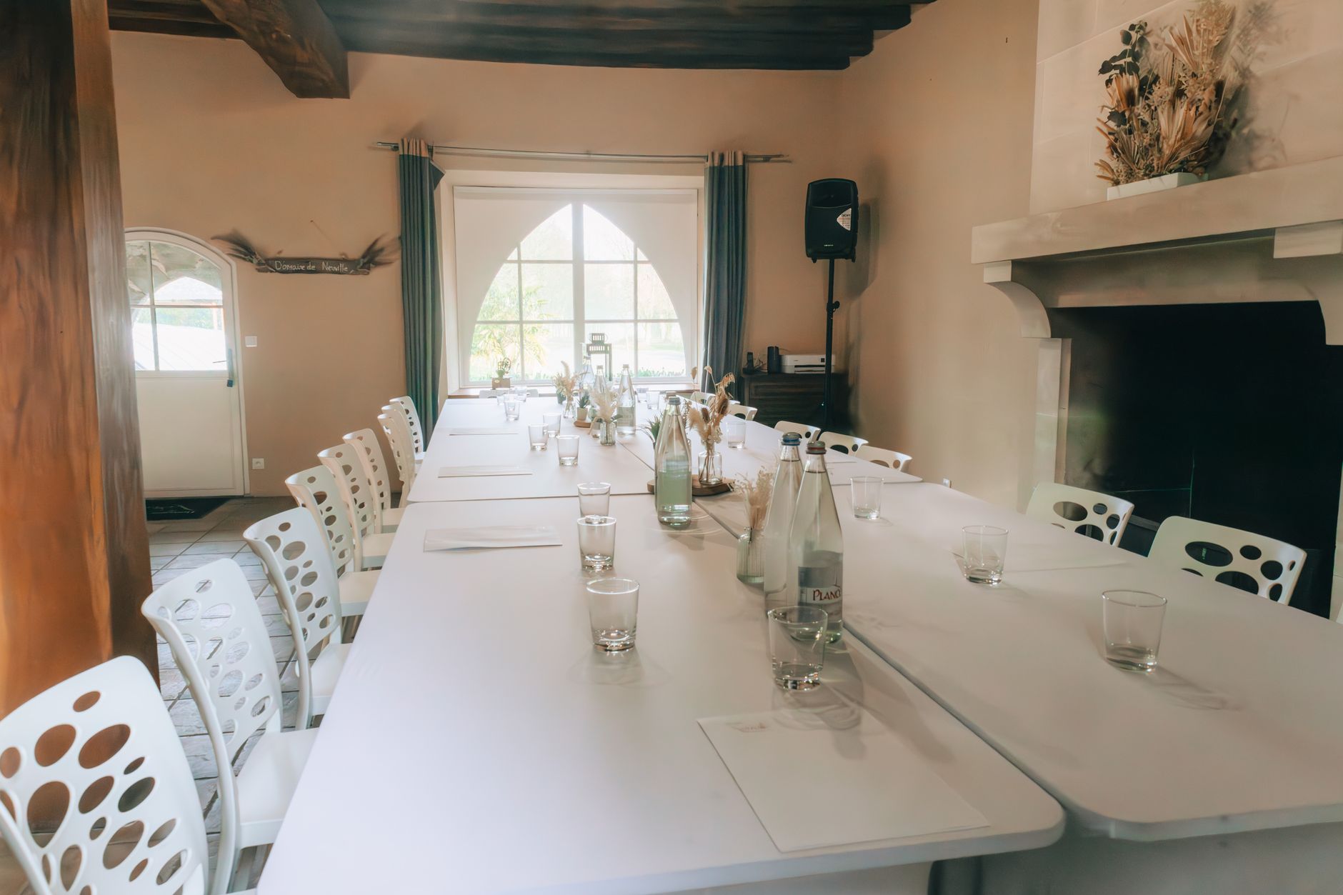 Spacious indoor conference room with a large table set for a meeting, featuring bottled water and minimalistic decor.
