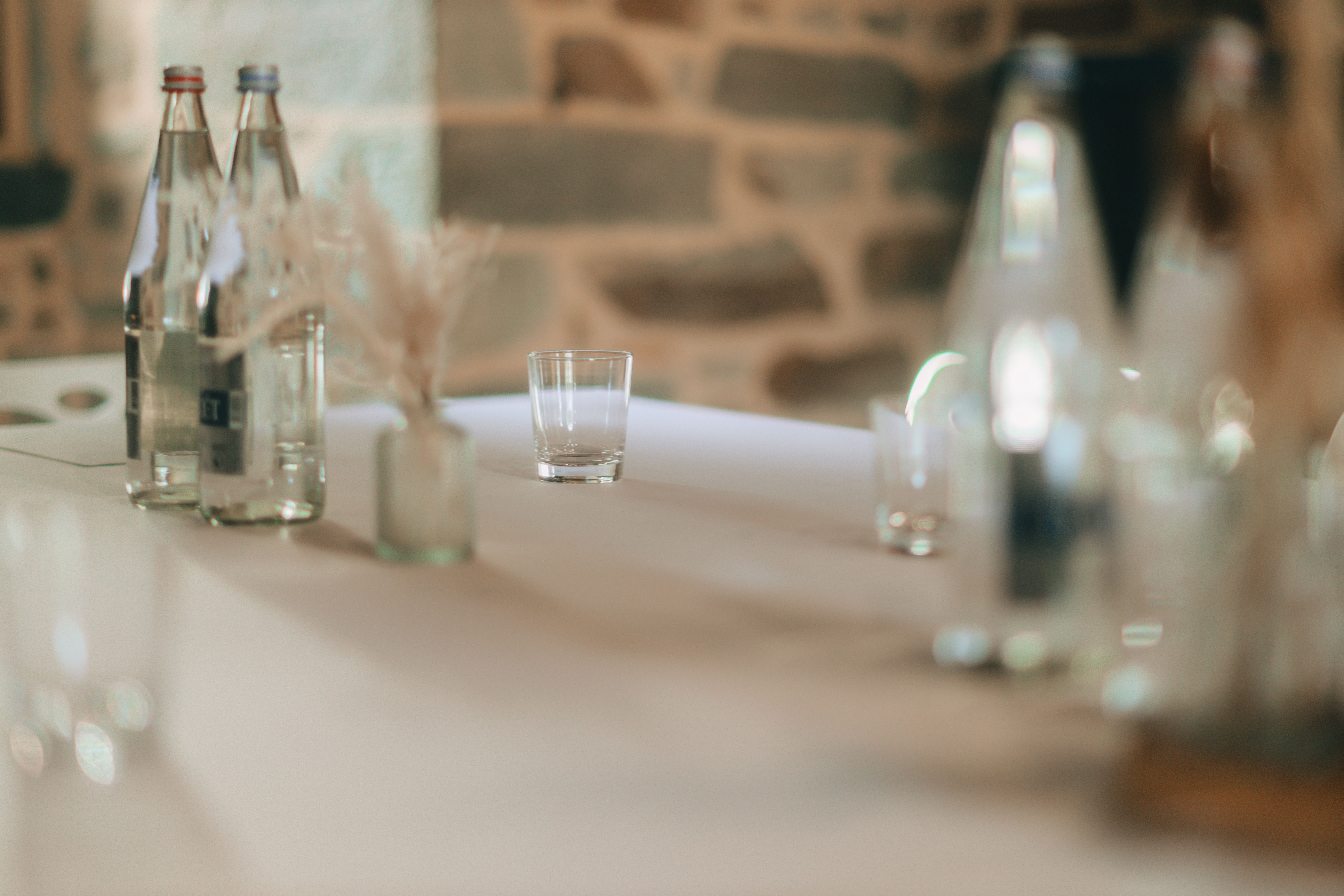 A refined table setting featuring bottled water and a glass, with a soft focus backdrop.