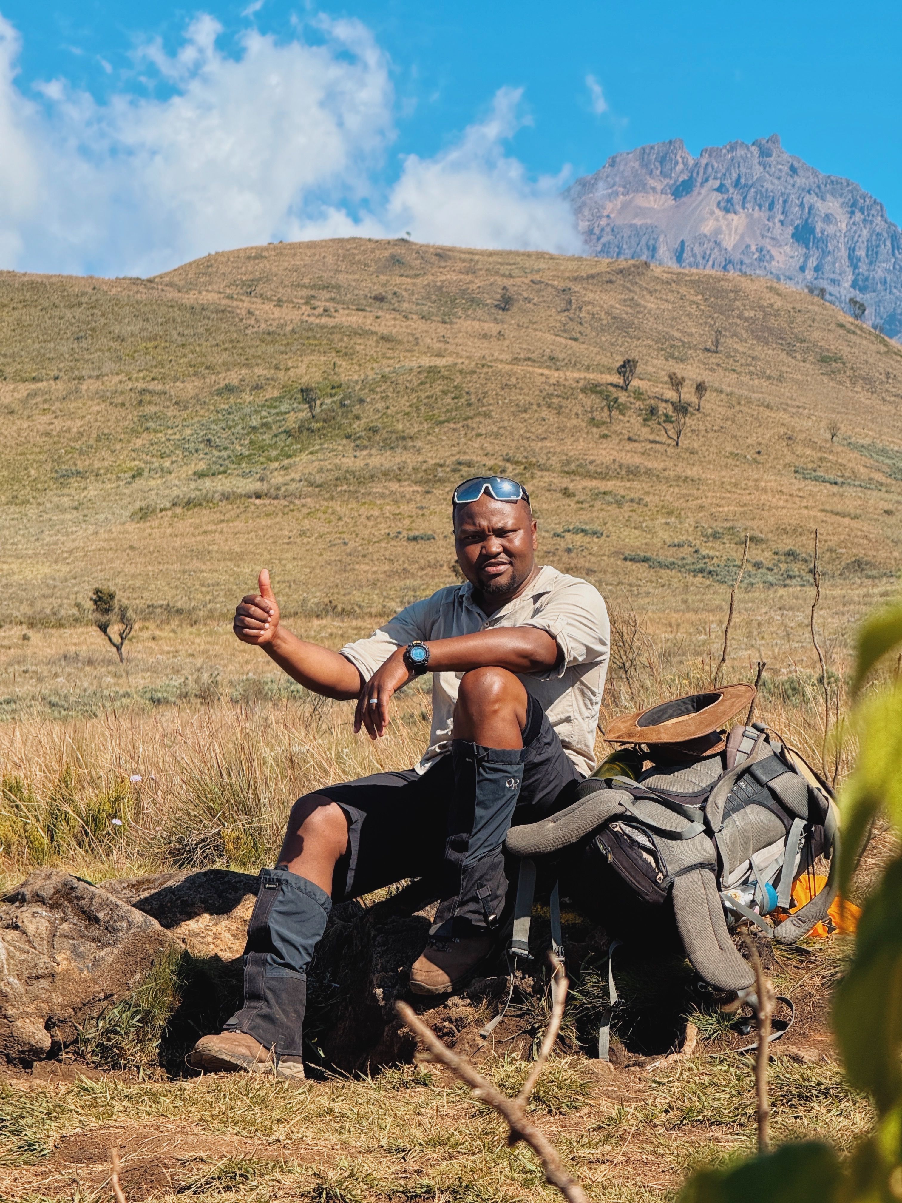 An adventurous hiker taking a break on the scenic Mount Kilimanjaro trail in Tanzania.