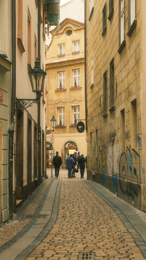 Free Charming cobblestone street in Prague with historic buildings and visitors. Stock Photo