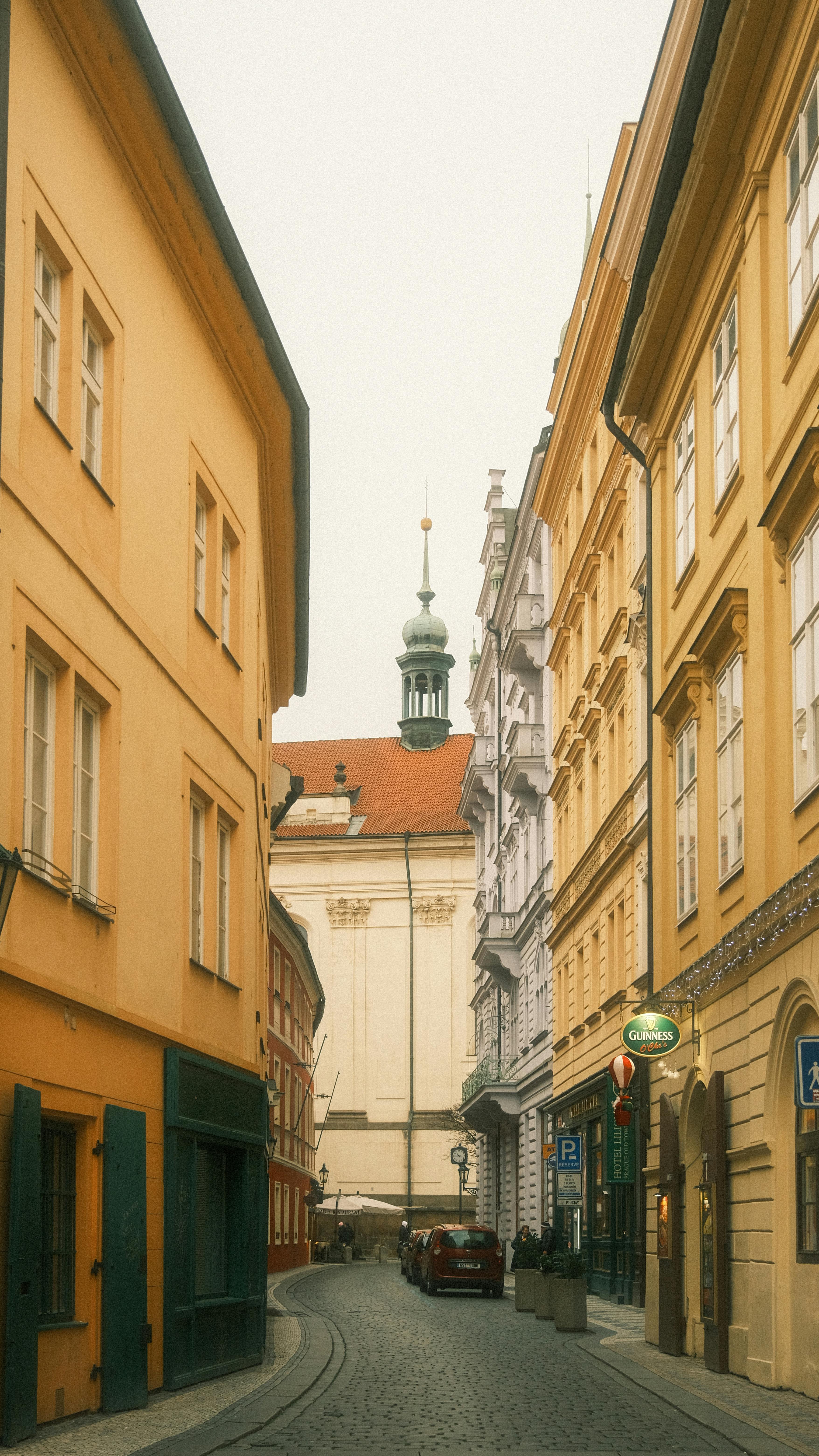 Narrow street with historic European architecture, leading to a charming spire.