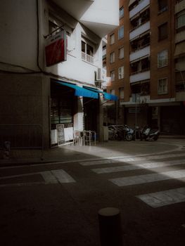 Sunlit Barcelona street corner with parked scooters and architectural charm.