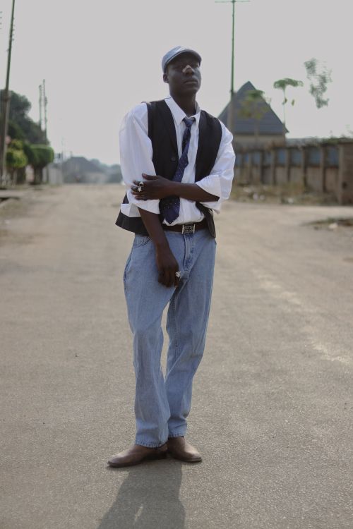 Free A fashionable young man in casual attire poses confidently on an empty street in Abuja, Nigeria. Stock Photo