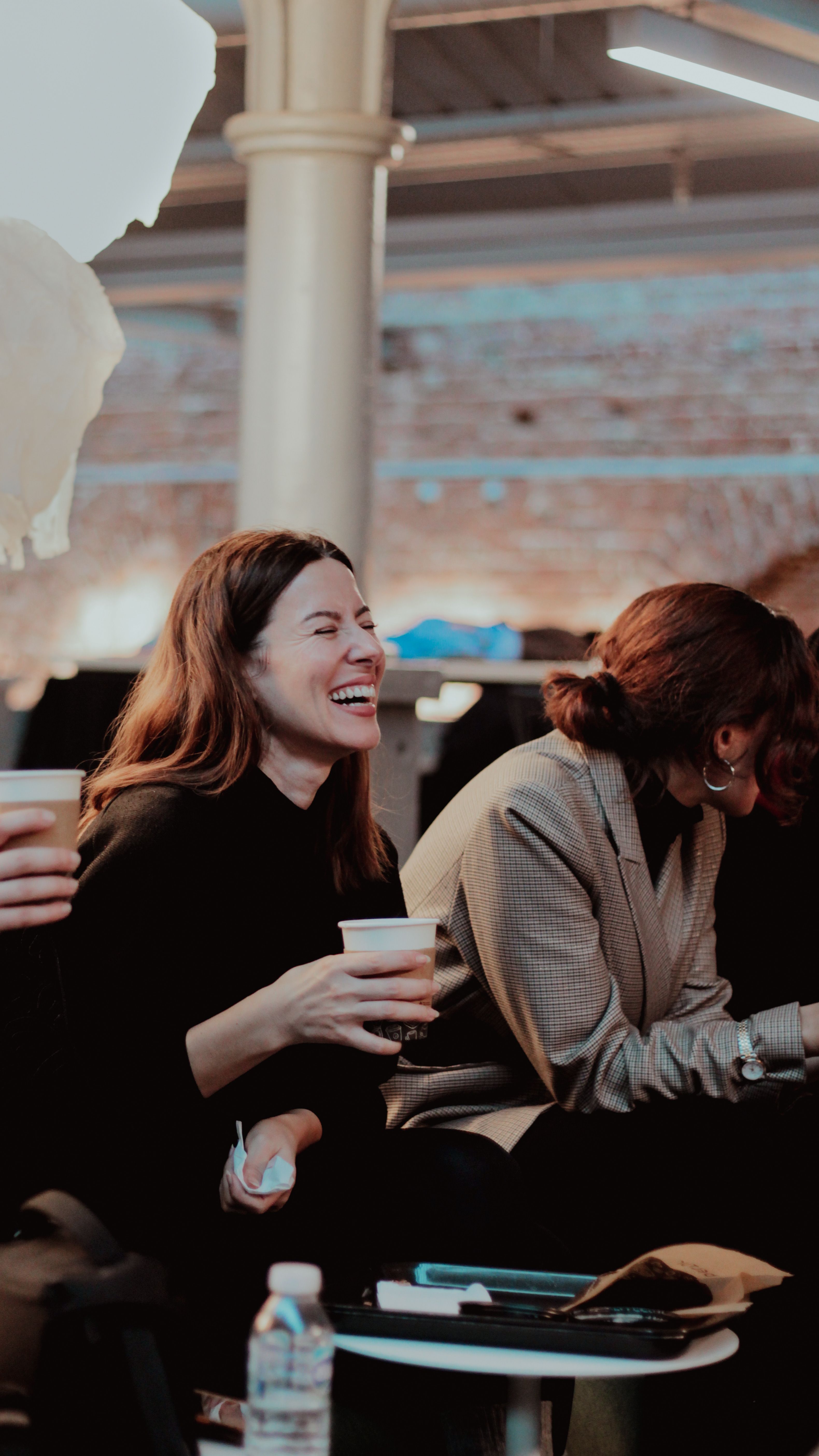 A group of adults enjoying a casual coffee break indoors, sharing laughter and conversation.