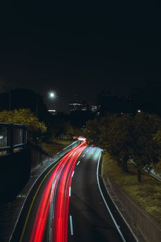 Dynamic night scene capturing vibrant red car light trails on a city road.